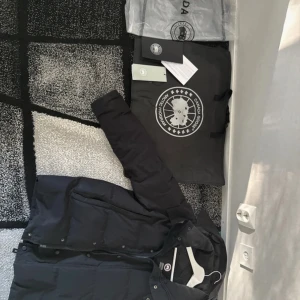Canada goose jacka äkta  - Säljer en svart jacka  från Canada Goose med klassisk patch på ärmen. Jackan har huva, dragkedja och knappar framtill samt två stora fickor. Perfekt för kalla vinterdagar och riktigt snygg streetstil. Lite smuts men kan tas bort med tvätt. Sliten men syns inte jätte mycket  men syns några märken sliten och en grej har jag lagt på slitna delen så ni vet syns i bilden den finns en hål men den är tejpad med svart som man kan se  Priset kan diskuteras via snabb affär. Så fråga frågor! 
