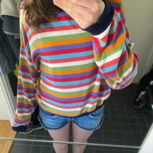 Färgglad randig tröja från Bershka - Säljer en superfin långärmad tröja från Bershka med färgglada ränder. Tröjan har mörkblåa muddar och krage, och är i mjukt material. Tunn stickad tröja. Nopprig men annars i fint skick☺️