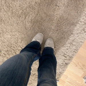 christian Louboutin - Säljer ett par vita sneakers från Christian Louboutin med coola silverfärgade nitar över tån och sidorna. Skorna har snörning och den klassiska röda sulan. Tillverkade i skinn med rund tå och platt sula. En nit har tyvärr lossnat och färgen på nitarna har också lossnat men inget man tänker på, sömnen har gått upp ( se bild) annars fungerar de bra. Dustbag och box medföljer.