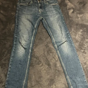 Levi's 512 Slim Taper jeans blå - Säljer ett par Levi's 512 Slim Taper jeans i klassisk blå tvätt med snygga slitningar. Jeansen har fem fickor, gul kontrastsöm och röd Levi's-tag på bakfickan. Modellen är smal med avsmalnande ben och passar perfekt för en trendig look.