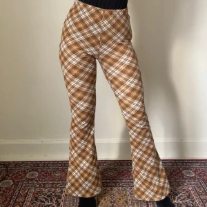 Bruna rutiga flared leggings från Topshop - Välkomna hösten i dessa brun- och vitrutiga flared leggings från Topshop. 🍂 Högmidjade i stretchigt material. Snyggt mönster, skön passform och är inte genomskinliga även när om du skulle dra till ett galet dansmove i dem. Perfekta för dig som gillar statement-plagg och vill sticka ut. Inga anmärkningar på skicket! 😊
