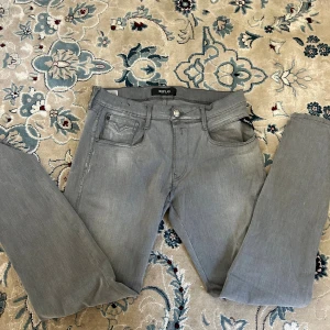 Grå jeans från Replay, storlek 32 - Säljer ett par grå jeans från Replay i storlek 32. Klassisk femficksmodell med Replay-logga på fickan och bakfickor med snygga sömdetaljer. Jeansen har rak passform och är tillverkade i mjukt denimtyg som sitter skönt hela dagen.