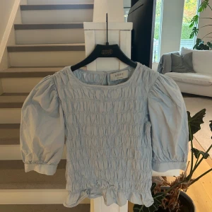 Ljusblå blus med puffärm från ADPT - Supersöt ljusblå blus från ADPT med puffiga trekvartsärmar. Storlek S! 