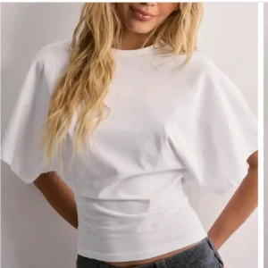 Nelly topp - Vit snygg topp med tajt midja och lösare upp till från Nelly i storlek S, endast använd 1-2 ggr