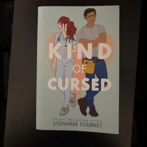 Kind of Cursed - En charmig bok med en illustrerad framsida som visar två unga vuxna – en sjuksköterska och en hantverkare. Perfekt för dig som gillar berättelser om relationer, vardagsliv och oväntade möten. Skriven av Amazon-bästsäljaren Stephanie Fournet.
