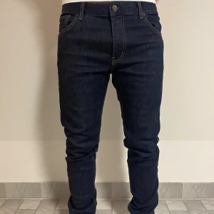 Mörkblå slim jeans från Weekday - Snygga mörkblå jeans från Weekday i skinny fit. Klassisk femficksmodell med kontrastsömmar och normal midja. Perfekta för dig som gillar en smal siluett och stilren look. Materialet är stretchigt jeans för extra komfort.