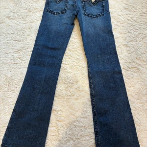 Blå bootcut jeans från Gina Tricot - Snygga blå jeans från Gina Tricot i storlek 164. Modellen har klassisk femficksdesign, bootcut-ben och normal passform. Jeansen är tillverkade i ett mjukt denimtyg med lätt tvättade detaljer för en cool look.