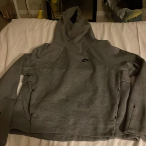 Grå hoodie från Nike  - Säljer en grå Nike hoodie i storlek ca 158-164 med svart Nike-logga på bröstet. Tröjan har huva, långa ärmar och praktiska fickor på sidorna. Perfekt för chill eller träning, mjukt material och klassisk stil.