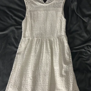Vit spetsklänning från Banner Barrett - Superfin vit kortklänning från Banner Barrett med broderad spets och ärmlös design. Klänningen har ett vackert mönster i spetsen, rund halsringning och knapp i nacken. Perfekt för sommarens alla tillfällen!