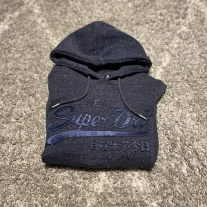 Superdry hoodie mörkblå - En mörkblå Superdry hoodie som passar i storlek S och är i väldigt bra skick det är bara att skiva vid eventuella frågor