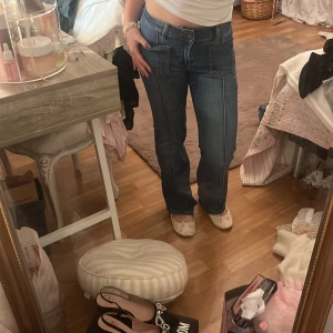 Blå bootcut jeans från Madlady - Säljer ett par blå bootcut jeans från Madlady med hög midja och snygga framfickor. Jeansen har markerade sömmar framtill och bakficka med knapp. Perfekt passform och cool retrostil.