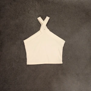 Vit croppad linnetopp med korsade band - Säljer en vit croppad linnetopp med snygga korsade axelband framtill. 