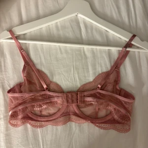 Rosa spetsbh från Hunkemöller - Säljer en superfin rosa spetsbh från Hunkemöller i storlek 75C. Blusen har justerbara axelband, hakknäppning bak och är tillverkad i transparent spets med snygga detaljer. Perfekt för dig som gillar romantisk och feminin stil. Själva bh-n är i jättefint skick, men det finns fläckar på ena bandet. 