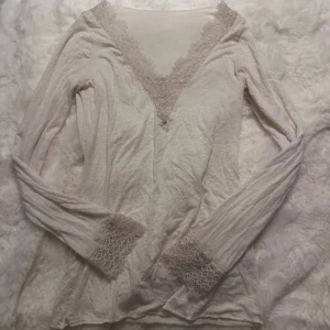 Vit intimissmi topp med spetsdetaljer  - Supersöt vit intimissmi topp med v-ringning och spetsdetaljer både vid halsringningen och vid ärmsluten. Tunn och mjuk i materialet, perfekt för lager-på-lager eller som den är. Ger en romantisk och chill vibe.