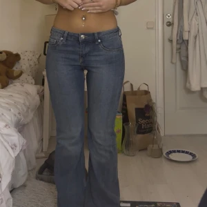 Blå bootcut jeans med låg midja - Snygga blå jeans med bootcut-modell och låg midja. Jeansen har klassisk femficksdesign och är tillverkade i ett mjukt denimtyg. Perfekta för dig som gillar en retroinspirerad look med utsvängda ben. Dom är i bra skick bortsett från hål i sömm längst ner!