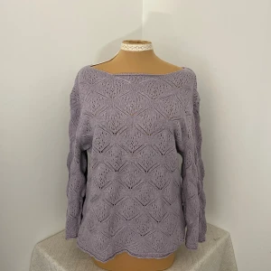 Ljuslila stickad tröja med mönster - Superfin ljuslila stickad tröja med lång ärm och snyggt hålmönster över hela plagget. Tröjan har en loose passform och bred halsringning som ger en chill vibe. Perfekt att styla med jeans eller kjol för en trendig look.