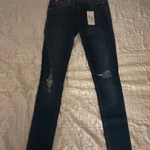 Mörkblå skinny jeans från 157 XXS - Snygga mörkblå skinny jeans från 157 i storlek XXS med slitningar på båda benen. Jeansen har midwaist och smal passform, perfekta för dig som gillar en tajt look. Klassisk femficksmodell och tillverkade i stretchig denim för extra komfort.