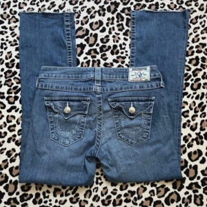True Religion blå bootcut jeans - Jag köpte dom av en tjej på Vinted som säger att dom ska se ut som dom gör nere vid benen och jag kan inte mer en lita på det!  Dom är värkligen jättesnygga men dom är tyvärr för korta för mig  Dom är i storlek w28 men skulle säga att dom är mindre då jag har ett annat par jeans i samma storlek från true religion som passar  Inga difekter!!  Midja:37cm Innerben:65cm Ytterben:90cm