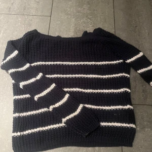 Svart stickad randig tröja från ONLY - Säljer en svart stickad tröja från ONLY i storlek XS. Tröjan har vita horisontella ränder och en half zip-dragkedja i nacken. Den är långärmad och har en grovstickad struktur som ger en cool och avslappnad vibe.