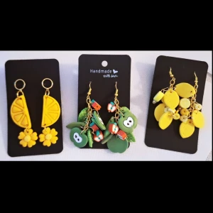 3 par handgjorda örhängen i Polymerclay "Ätbart" - Tre par färgglada handgjorda örhängen med fruktmotiv. Ett par med gula citronskivor och blommor, ett par med gröna äpplen och små fruktdetaljer, och ett par med citroner och lime i olika nyanser av gult. Alla har guldfärgade krokar och detaljer. Allergivänligt ❤️