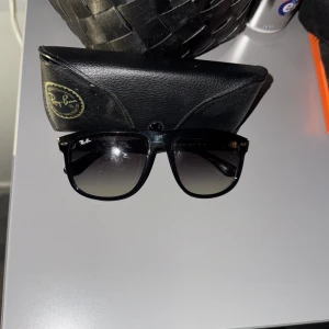 Svarta Ray-Ban boyfriendsolglasögon - Snygga svarta Ray-Ban boyfriend solglasögon med klassisk fyrkantig form och mörktonade linser. Kommer med original Ray-Ban fodral och putsduk. Perfekt accessoar för soliga dagar och en ikonisk look. Knappt använda.