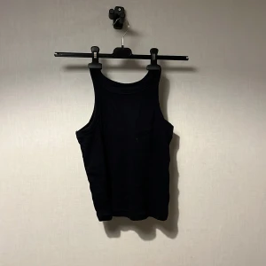 Svart linnetopp från Kappahl - Svart linnetopp från Kappahl i storlek 158/164. Modellen är klassisk med rundad hals och breda axelband. Materialet är mjukt och stretchigt, perfekt för en chill och enkel stil. Passar dig som gillar basic och stilrena plagg.