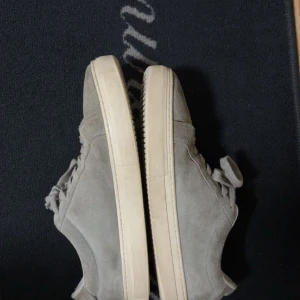 Gråa mockaskor från Vagabond  - Snygga grå sneakers i mocka med platt, vit sula och klassisk snörning. Skorna har en stilren och enkel design som passar till det mesta. Perfekta för dig som gillar en clean och avslappnad look.