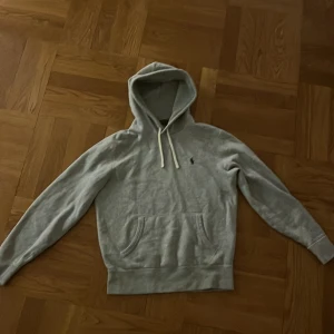  Polo Ralph Lauren hoodie - Fräsch grå hoodie från Polo Ralph Lauren i storlek S med klassisk broderad logga på bröstet. Tröjan har huva med snörning, magficka och långa ärmar. Ord pris 1700 sek. Skick 9/10 