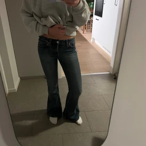 Blå bootcut jeans från Monki - Säljer ett par blå bootcut jeans från Monki med klassisk femficksdesign och snygga slitningar. Jeansen har låg midja och är tillverkade i jeansmaterial med orangea kontrastsömmar. Perfekta för dig som gillar en retro vibe och vill ha ett par riktigt schyssta jeans.❣️❣️