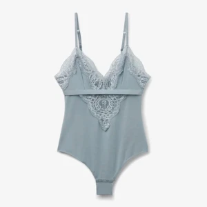 Ljusblå spetsbody med smala axelband - Supersnygg ljusblå body med tunna, justerbara axelband och v-ringad spetsdetalj framtill och baktill. Bodyn har en tight passform och är tillverkad i mjukt material med dekorativ spets längs kanterna för en extra feminin touch.