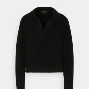 Svart stickad tröja med krage från Monki - Svart stickad tröja från Monki med snygg krage och v-ringad hals. Tröjan har lång ärm och ribbade muddar vid ärmslut och nederkant. Perfekt för lager-på-lager och chill stil.