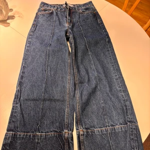 Wide jeans från Zara i blå denim - Säljer ett par blå jeans från Zara i storlek 34. Modellen har breda ben, hög midja och markerade sömmar längs benen. Klassisk femficksdesign och coola detaljer med extra söm vid benslut. Perfekta för dig som gillar en avslappnad och trendig look.