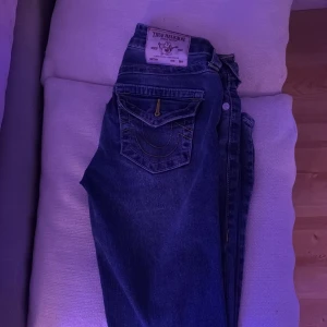 True Religion Becca Bootcut Jeans -  Antingen Säljer eller byter  ett par snygga True Religion Becca jeans i klassisk blå tvätt med coola kontrastsömmar och ikoniska fickdetaljer. Modellen är midwaist med bootcut-ben, vilket ger en schysst siluett. Materialet är slitstarkt jeans och passformen är normal.