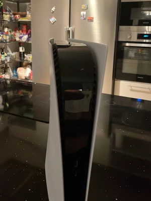 PlayStation 5 spelkonsol vit - Säljer en PlayStation 5 spelkonsol från Sony. Konsolen har en futuristisk design med vita sidopaneler och svart mittparti. Tillverkad i plast och har PlayStation-loggan på sidan. Perfekt för gaming och underhållning. Kommer ochså med en helt ny laddare till kontrollen och ström kabel till ps5!