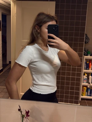 Vit ribbad topp - Säljer en vit ribbad  topp med korta ärmar och rund halsringning. Toppen har en tight passform och är tillverkad i ett stretchigt material som sitter snyggt på kroppen. Perfekt att matcha med jeans eller kjol. Helt oanvänd nypris 200kr