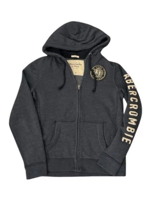Mörkblå zip hoodie från Abercrombie - Snygg mörkgrå hoodie från Abercrombie & Fitch med dragkedja, huva med dragsko och stora fickor framtill. Logga på bröstet och texten 'ABERCROMBIE' längs ena ärmen i vitt. Tillverkad i mjukt bomullsmaterial, perfekt för en avslappnad look.