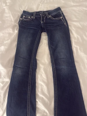 Mörkblå bootcut-jeans från Big Star - Snygga mörkblå jeans från Big Star med kontrastsömmar och dekorativa fickor bak. Modellen har bootcut-ben och klassisk femficksdesign. Perfekta för dig som gillar en lite bredare passform nertill och detaljerade fickor.