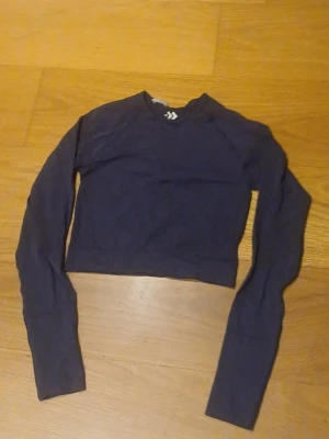 Mörkblå croppad långärmad träningstopp - En stilren mörkblå croppad topp med långa ärmar och rund hals. Perfekt för träning eller en chill look. Tunt och stretchigt material som sitter tight mot kroppen. 😊💕