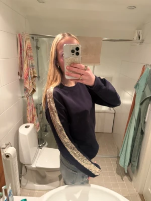 Mörkblå sweatshirt med paljettband - Jätte snygg mörkblå tröja med guldiga ränder på sidorna, säljs då den inte används längre