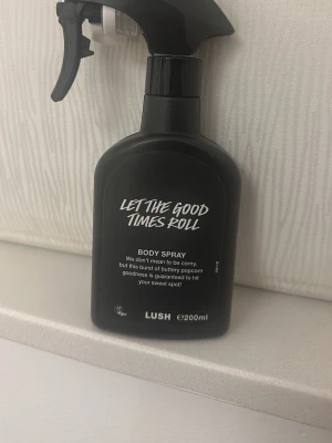 Let The Good Times Roll Body Spray - En svart sprayflaska med body spray från Lush, doften heter Let The Good Times Roll och innehåller 200 ml men är använd ungefär 100 ml kvar. Doften beskrivs som smörig popcorn-goodness.