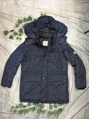 Moncler Ales dunparka storlek 5 - |Färg: Navy/mörkblå, matt, fläckar/slitage | Modell: Ales, dunparka, huva | Storlek: 5 (XL), rymlig passform | Skick: Grade B+, 8/10 (missfärgningar) | Hör av dig ifall du har funderingar!