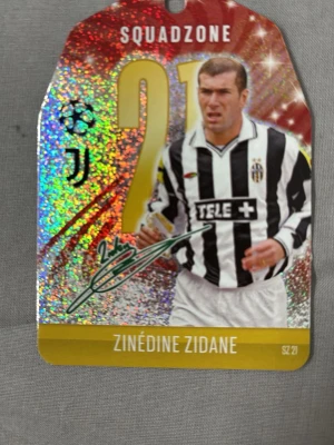 Match Attax Squadzone Zidane kort - Exklusivt samlarkort från Match Attax Squadzone med Zinedine Zidane i Juventus tröja, nummer 21. Kortet har holografisk yta och tydlig signaturtryck. Perfekt för fotbollsfans och samlare av sportkort. Köparen står för frakten.