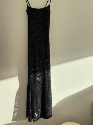 Svart långklänning med paljetter - Långklänning euforia från Bikbok med smala axelband och glittriga paljetter över hela klänningen. Klänningen har en figurnära passform, använd en gång. 