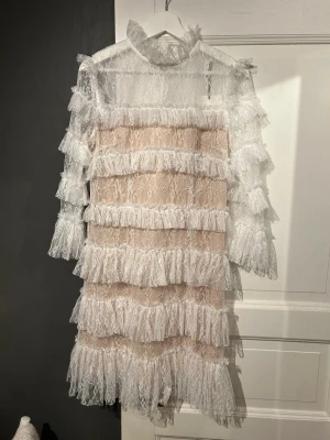 Vit spetsklänning med volanger från By Malina - Superfin kort vit spetsklänning från By Malina som är perfekt till skolavslutning eller student. Helt ny, säljer eftersom jag köpt en annan. Nypris 2800 kr. Storlek M men passar mig som är S.