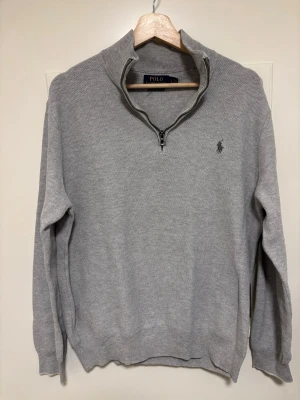 Grå half zip tröja Polo Ralph Lauren - Snygg grå tröja från Polo Ralph Lauren med half zip och hög krage. Tillverkad i mjuk pima bomull och har det klassiska broderade logotypen på bröstet. Skick 9/10, Storlek L men passar mer som en M. Skriv vid funderingar!!