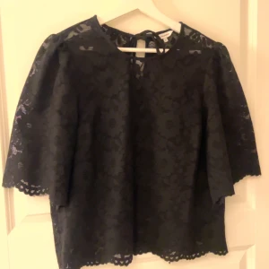 Svart blommig spetsblus med puffärm - Snygg svart blus i spets med blommigt mönster och puffiga trekvartsärmar. Stolek M ifrån bubbleroom. Använd 2 gånger så är i jättebra skick.