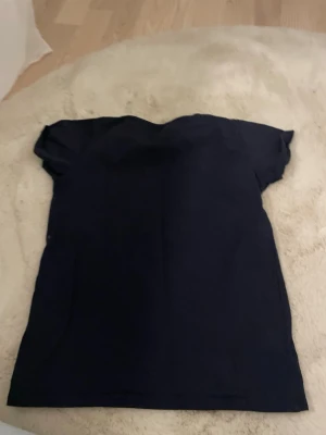 Mörkblå basic t-shirt från lager 157 - En enkel och stilren mörkblå t-shirt från lager 157. T-shirten har korta ärmar och en klassisk rund halsringning. Perfekt för en avslappnad look och lätt att matcha med andra plagg.