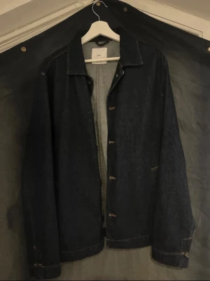 Mörkblå jeansjacka från MNG - Klassisk mörkblå jeansjacka från MNG med raka linjer och enkel design. Jackan har knappar framtill, krage och långa ärmar. Tillverkad i slitstarkt denimtyg som ger en tidlös look. Perfekt att slänga över en hoodie eller t-shirt. Originalpris : 899 kr