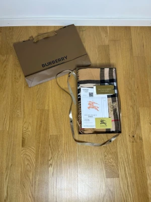 Burberry Kashmir Halsduk Beige One size - Klassisk beige halsduk från Burberry med det ikoniska rutmönstret i svart, vitt och rött. Halsduken har fransar i ändarna och är tillverkad i ett mjukt material som känns lyxigt. Perfekt accessoar för att lyfta din outfit.
