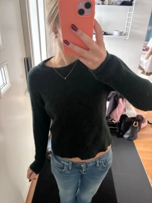 Mörkgrön stickad tröja - Mysig mörkgrön stickad tröja med lång ärm och rund halsringning. Tröjan har en något kortare passform.